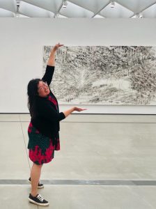Dr. Christine Hahn pretending to hold an artwork in a museum