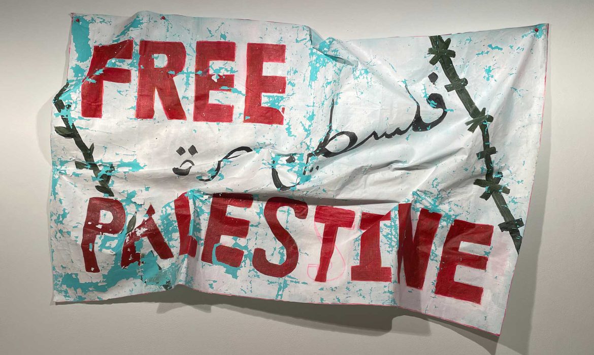 A hand-painted banner reading "Free Palestine." The banner is wrinkled and the paint is cracking.