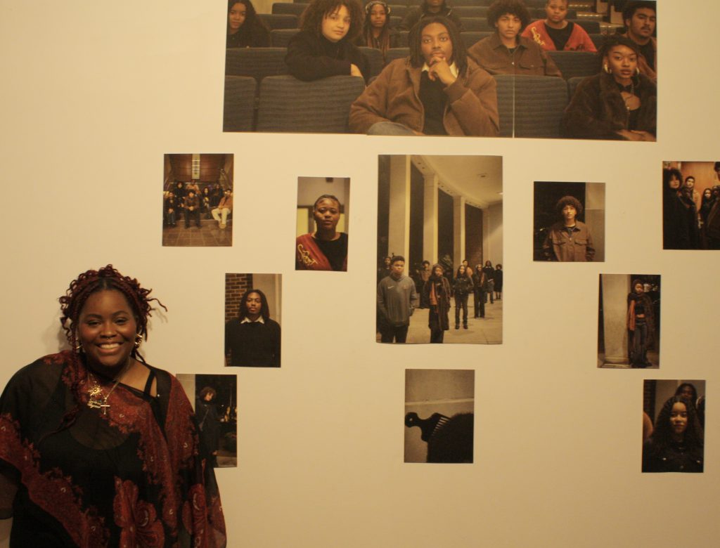 Student (Shyane Barnes-Taylor) stands next to her Black Student Organization photographs